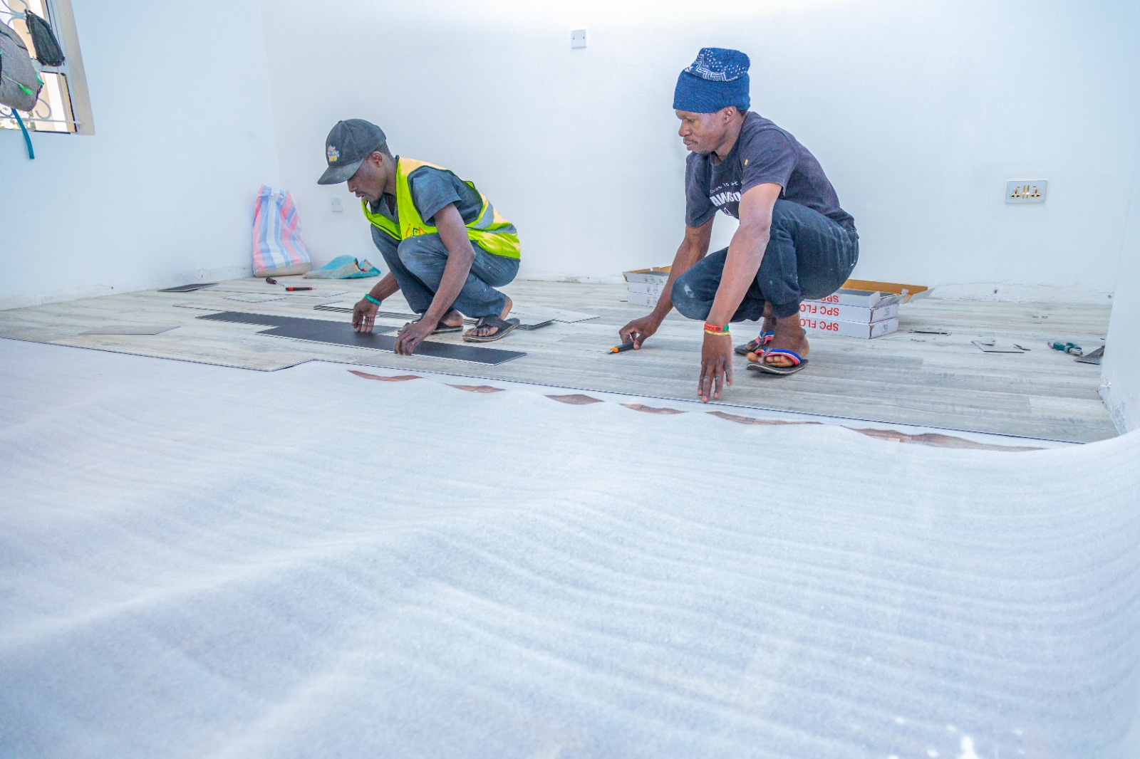 Two fitters laying SPC planks over acoustic underlayment